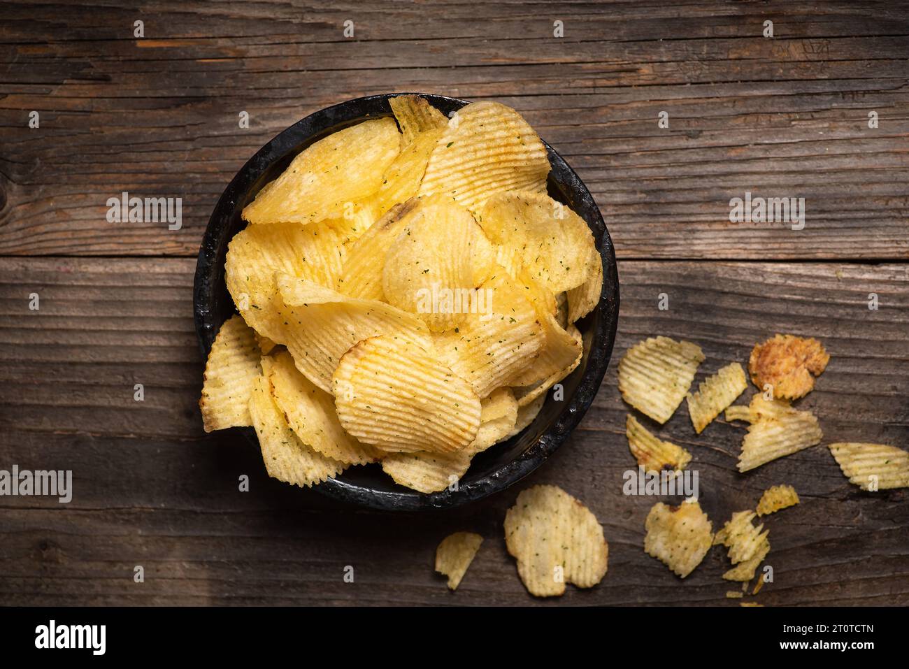 Knusprige Kartoffelchips in einer Schüssel auf hölzernem Hintergrund Stockfoto