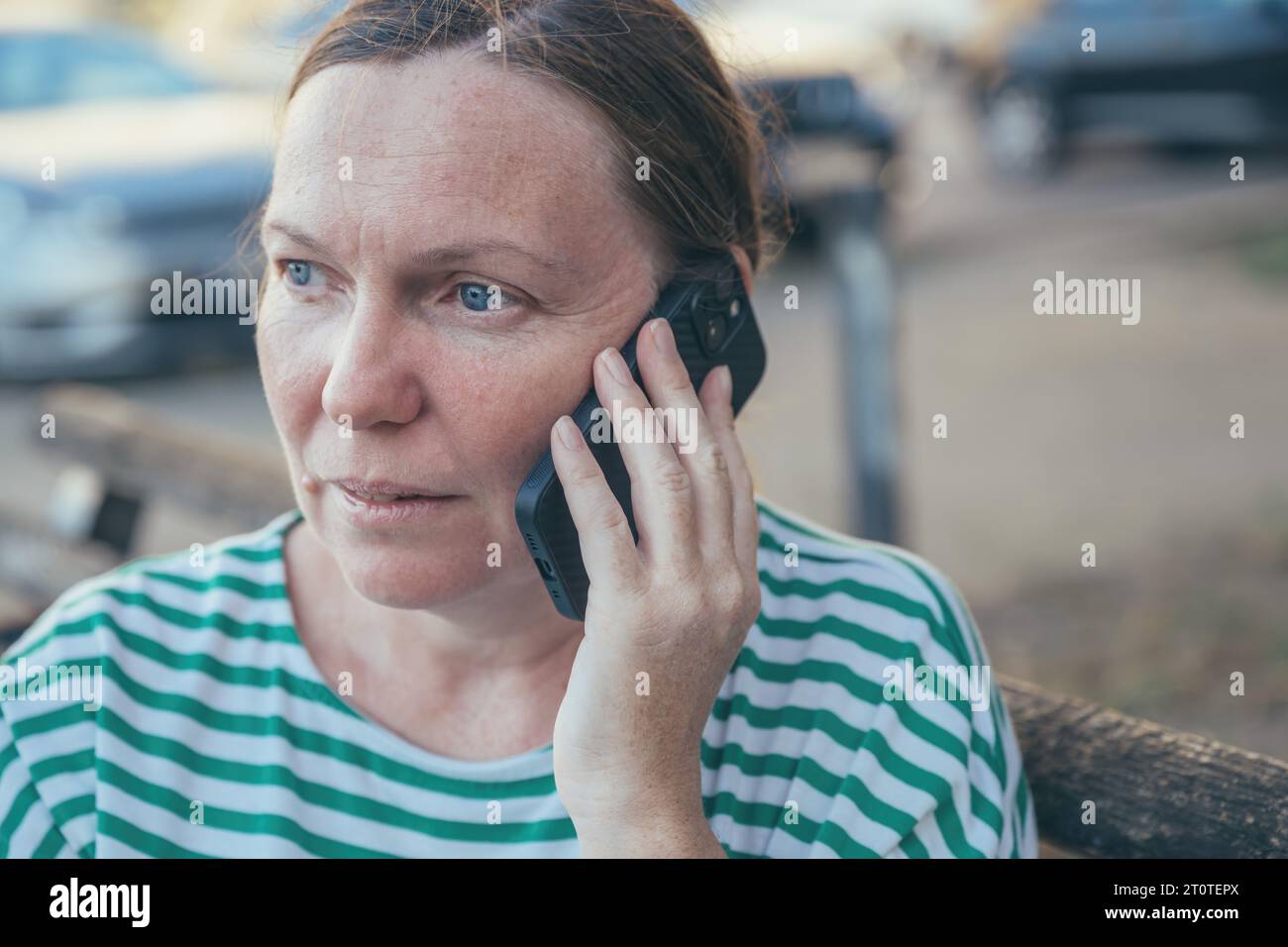 Ernsthaft besorgte Frau, die draußen auf der Straße auf dem Handy spricht, selektiver Fokus Stockfoto