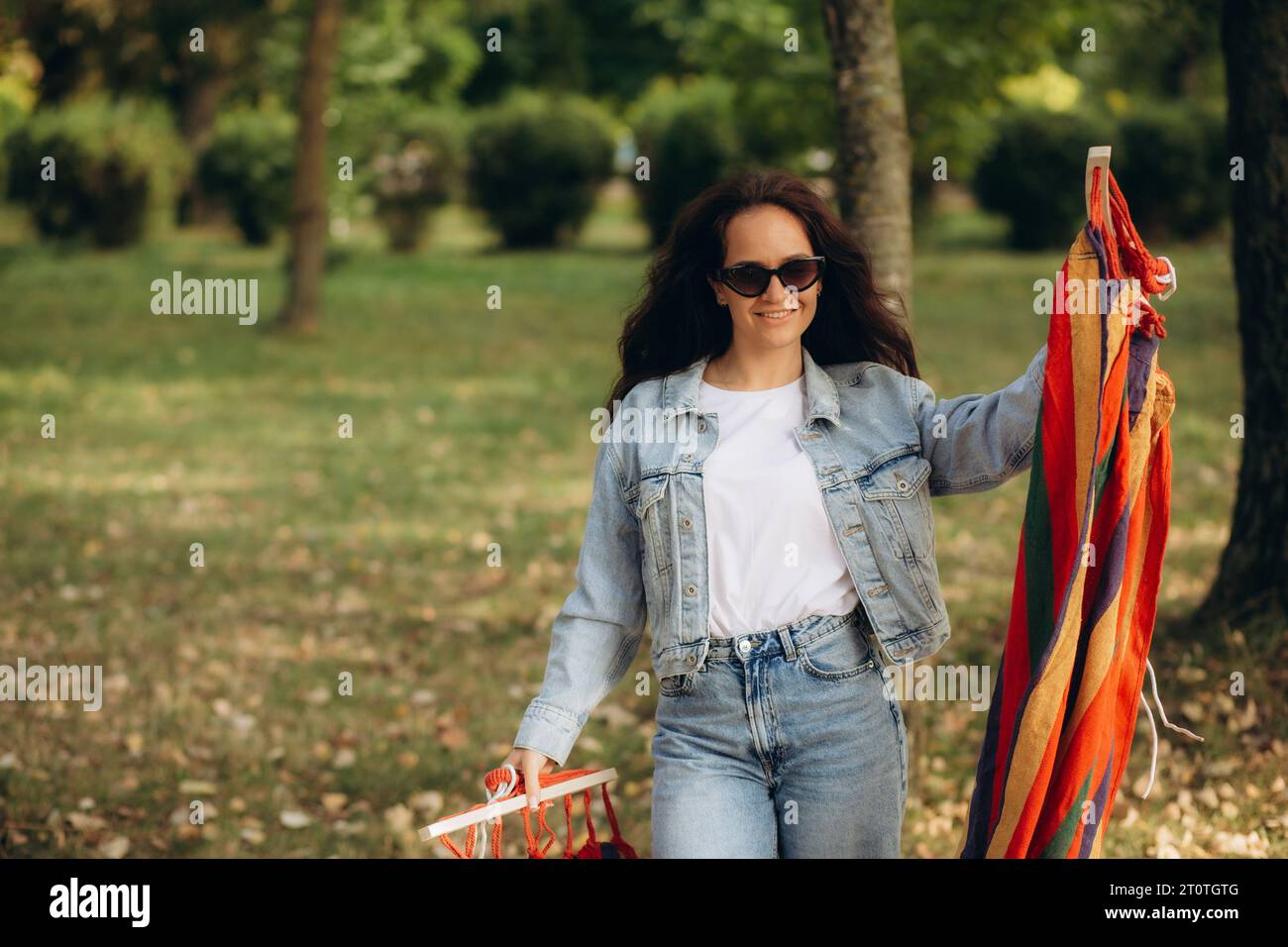 Eine Frau entfaltet sich und fesselt eine Hängematte an einen Baum Stockfoto