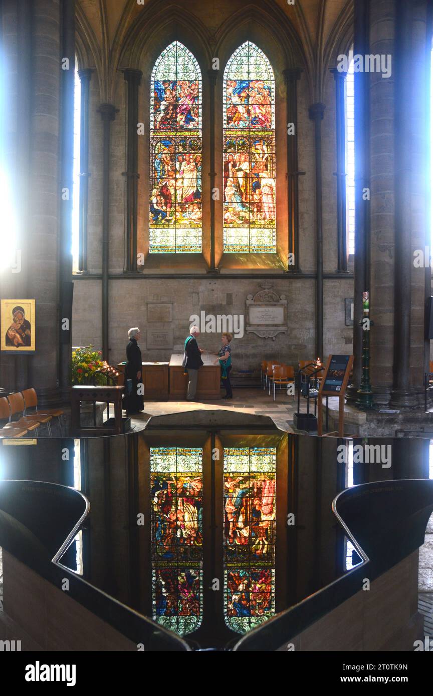 Reflexion von Witwen aus Buntglas im Wasser der Taufschrift in der Anglican Cathedral Church in Salisbury, Wiltshire, England, Großbritannien. Stockfoto