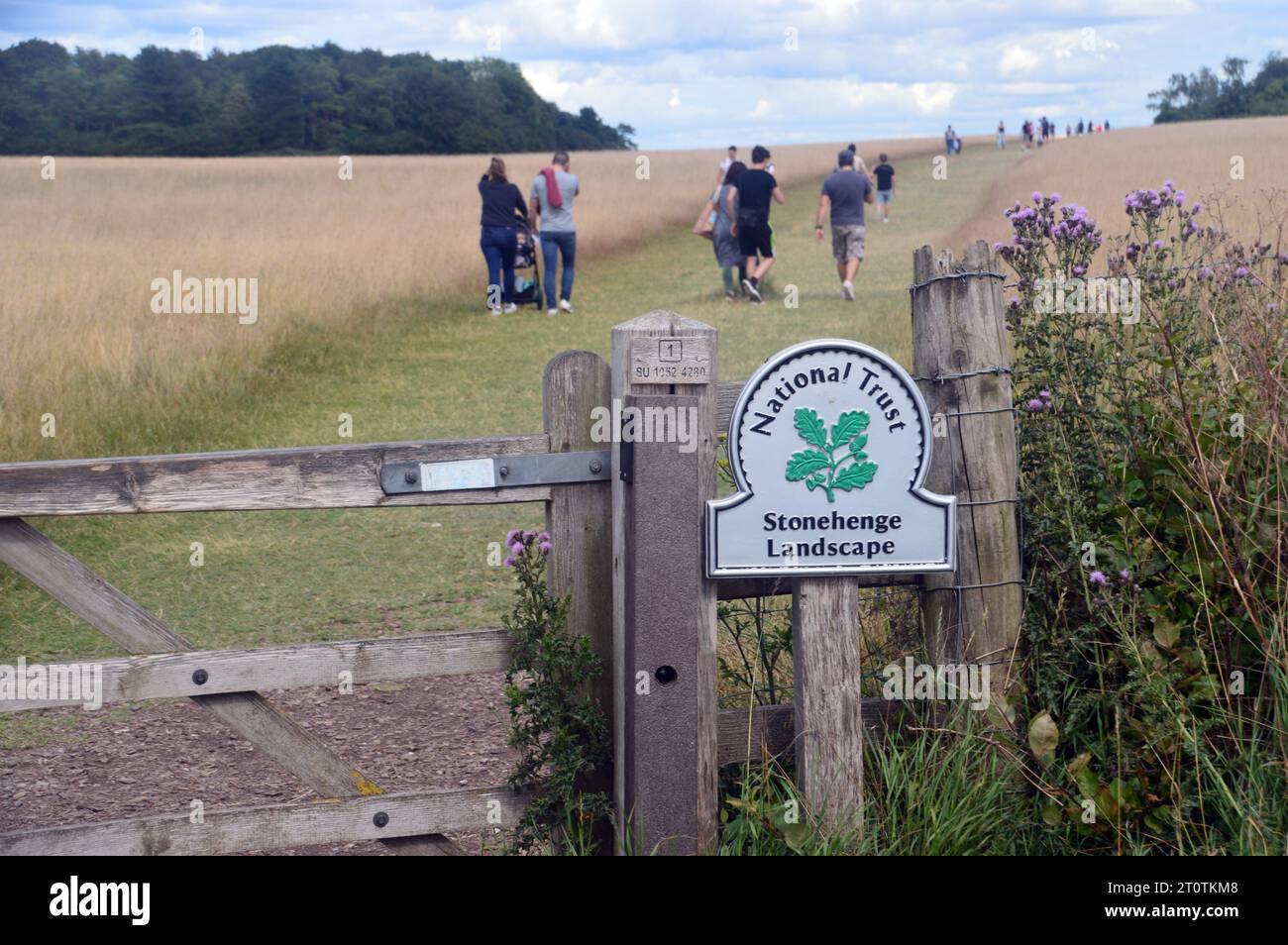 Menschen gehen am National Trust Wegweiser und Wooden Gate auf dem Weg nach Stonehenge vom Visitor Exhibition Centre auf der Salisbury Plain, Wiltshire, England Stockfoto