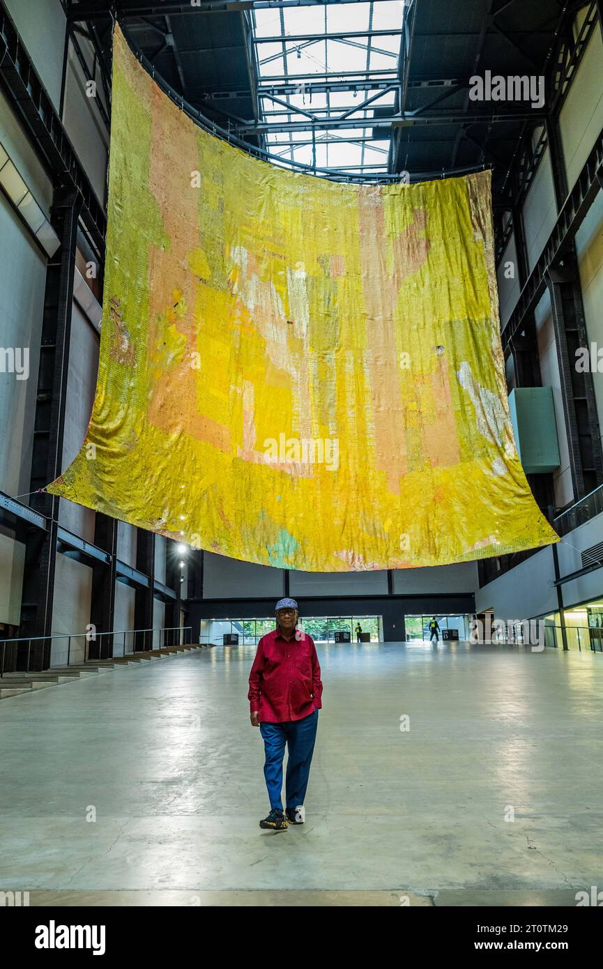 London, Großbritannien. Oktober 2023. Hyundai-Kommission: El Anatsui (Bild): Hinter dem Roten Mond in der Turbinenhalle der Tate Modern. Bilder SOLLTEN NUR verwendet werden, wenn sie auf diese Installation verweisen. El Anatsui, der in Ghana geboren und in Nigeria ansässig ist, ist vor allem für seine kaskadierenden metallischen Skulpturen bekannt, die aus Tausenden von recycelten Flaschenoberflächen bestehen, die mit Kupferdraht gekoppelt sind. Anatsuis Arbeiten widmen sich Themen wie Umwelt, Konsum und Handel. Guy Bell/Alamy Live News Stockfoto