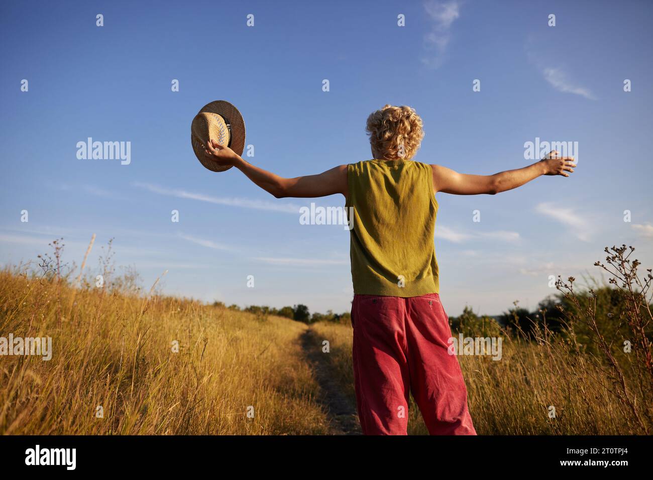 Glücklicher junger Mann mit erhobenen Händen, der die Natur genießt Stockfoto
