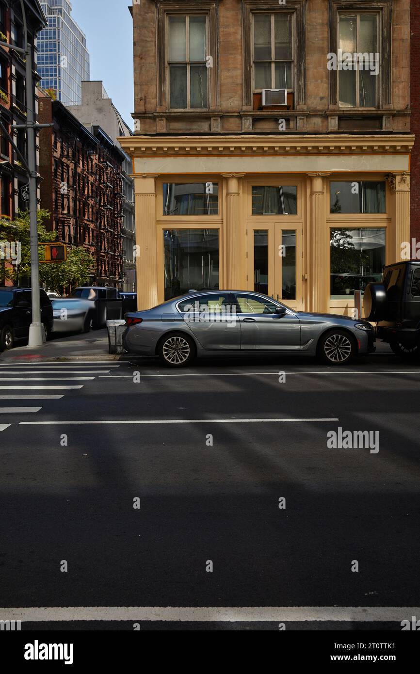 Autos auf Fußgängerüberquerung in der Nähe des Gebäudes mit Glasvitrinen auf der Avenue in New york, City Vibes Stockfoto