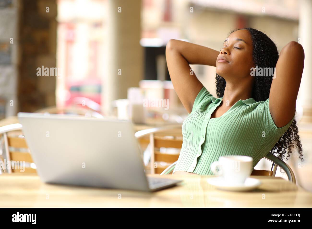 Schwarze Frau mit Laptop zum Ausruhen und Entspannen auf einer Restaurantterrasse Stockfoto