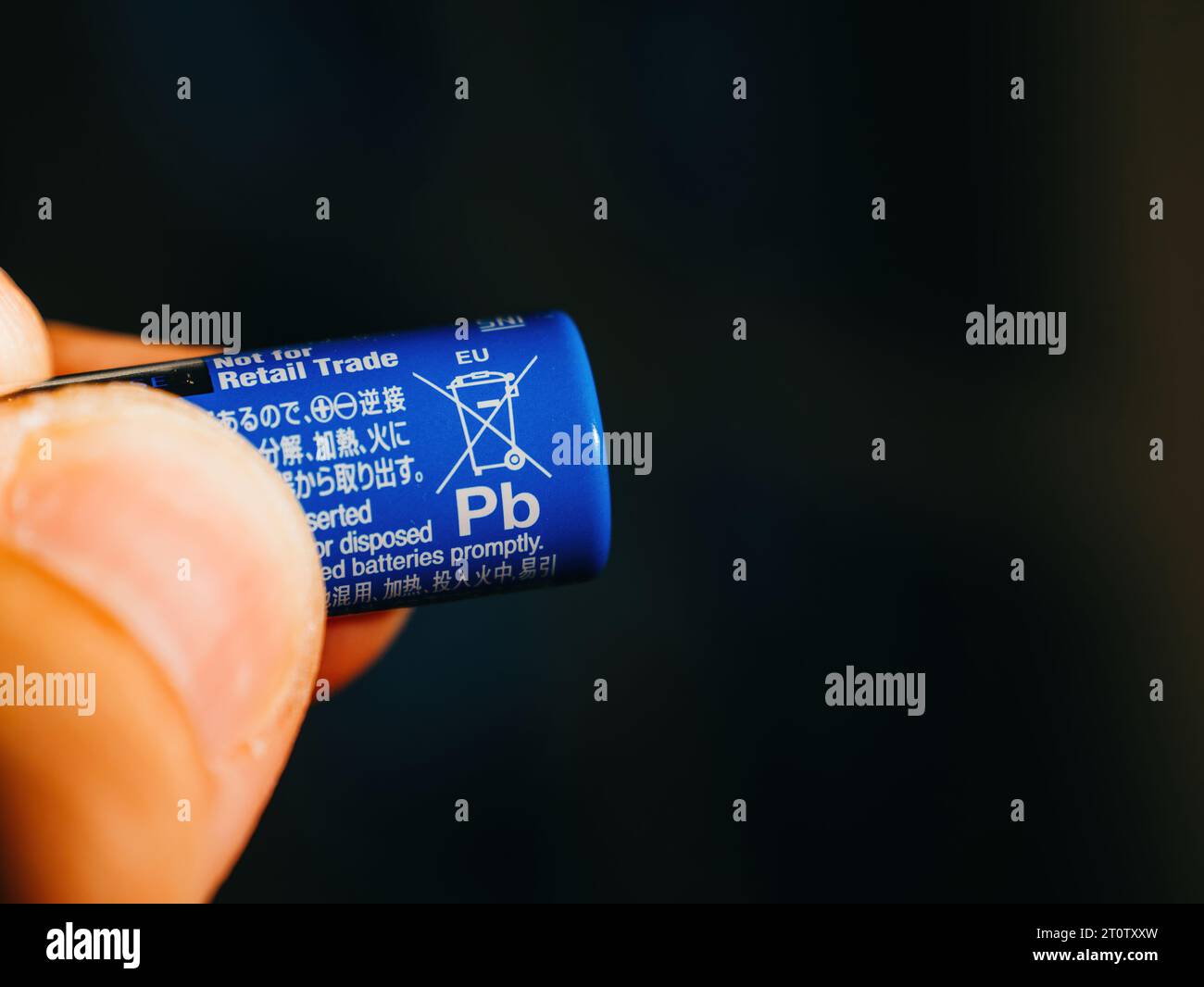Lyon, Frankreich - 6. September 2023: Eine männliche Hand hält eine blau gefärbte Panasonic AA-Batterie, die ein nicht Pb enthaltendes Schild vor einem unscharfen schwarzen Hintergrund aufweist. Stockfoto