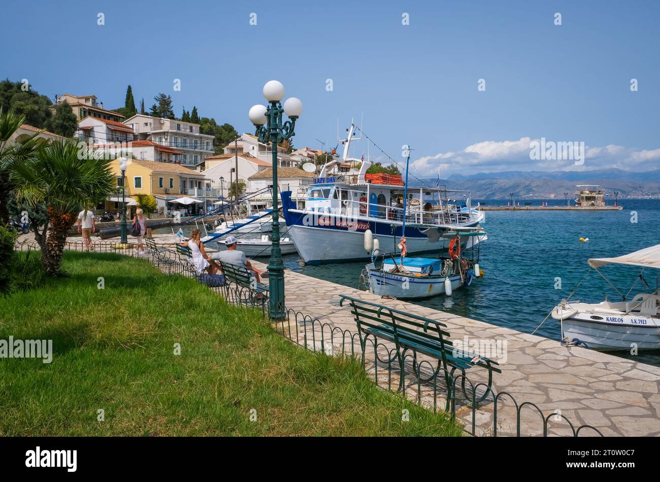 Kassiopi, Korfu, Griechenland - Fischerboote und ein Ausflugsboot im Hafen von Kassiopi, einer kleinen Hafenstadt im Nordosten der griechischen Insel Cor Stockfoto