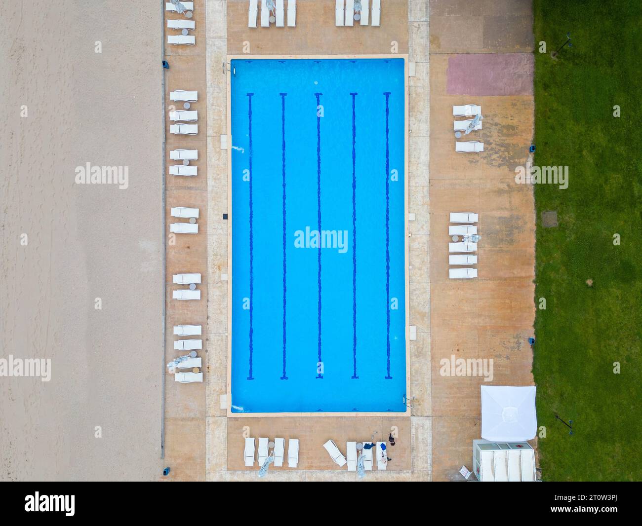 Aus der Vogelperspektive ist ein leerer Pool ohne Schwimmer sichtbar. Das ruhige Wasser spiegelt die Umgebung wider und schafft eine friedliche Atmosphäre. Ohne jemanden in der Nähe, Stockfoto