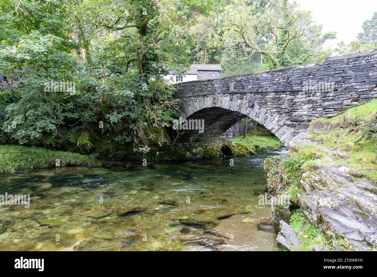 Elterwater Dorf und Brücke im Lake District, River Brathay fließt unter dieser denkmalgeschützten Brücke aus dem 18. Jahrhundert, Cumbria, England, Großbritannien Stockfoto