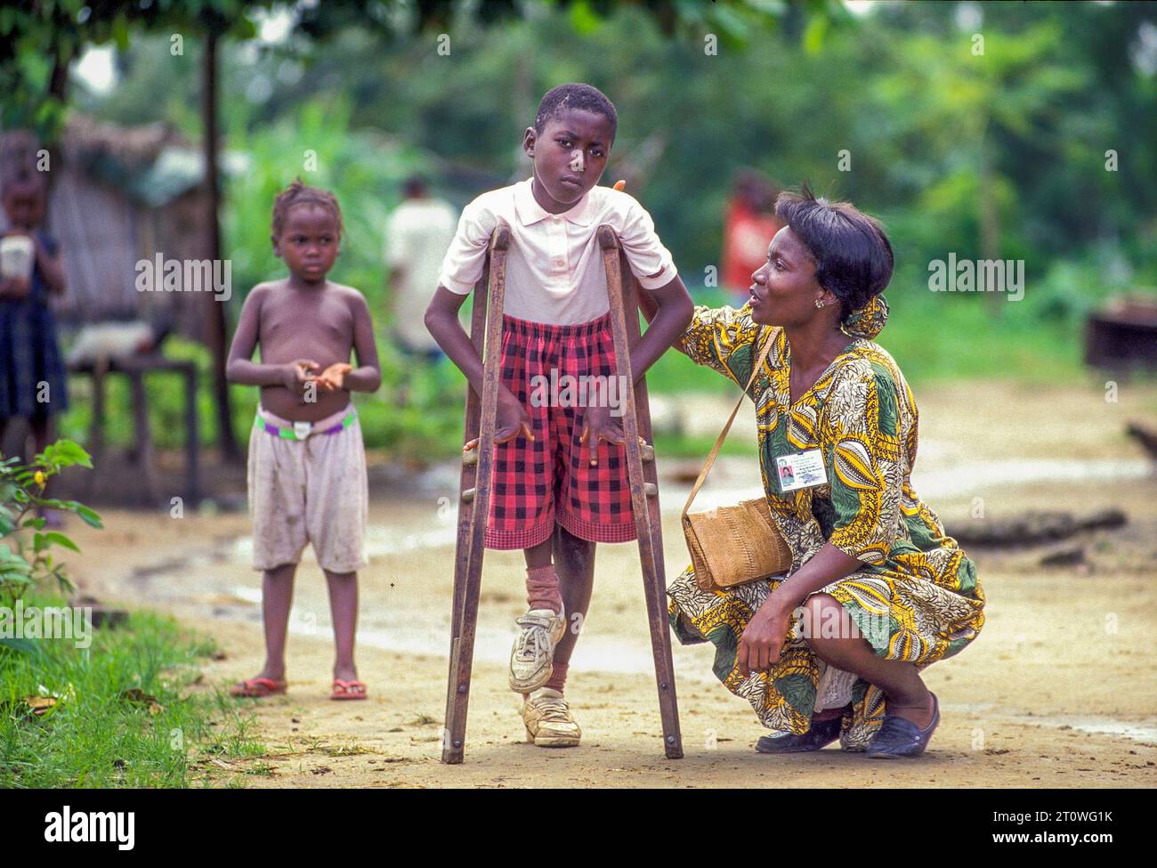 Liberia, Region Monrovia; Opfer des Bürgerkriegs. Porträt eines auf Krücken gehenden Kindes und eines Sozialarbeiters. Stockfoto