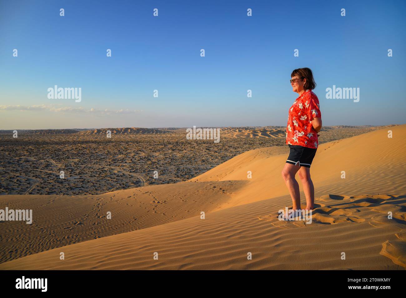 Frau, die den Sonnenuntergang über den Sanddünen der Arabischen Wüste in Oman beobachtet Stockfoto