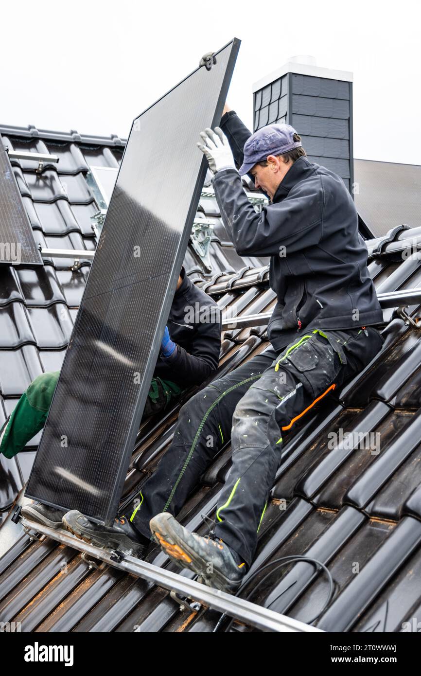 Techniker, die Solarpaneele auf dem Dach eines Hauses installieren Stockfoto