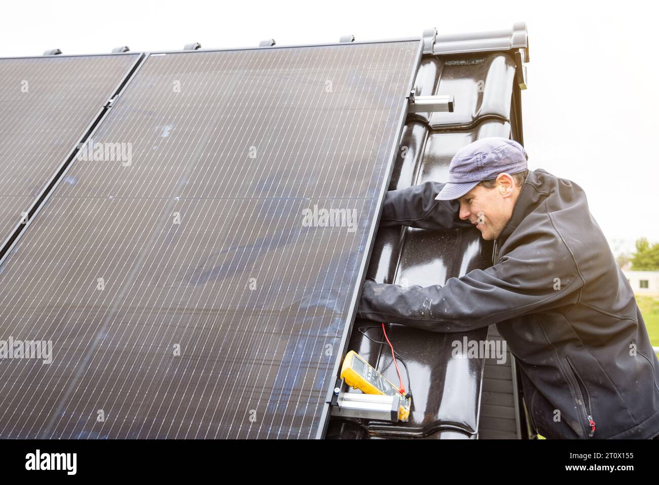 Elektriker, der an der Installation eines Sonnenkollektors auf einem Dach arbeitet Stockfoto