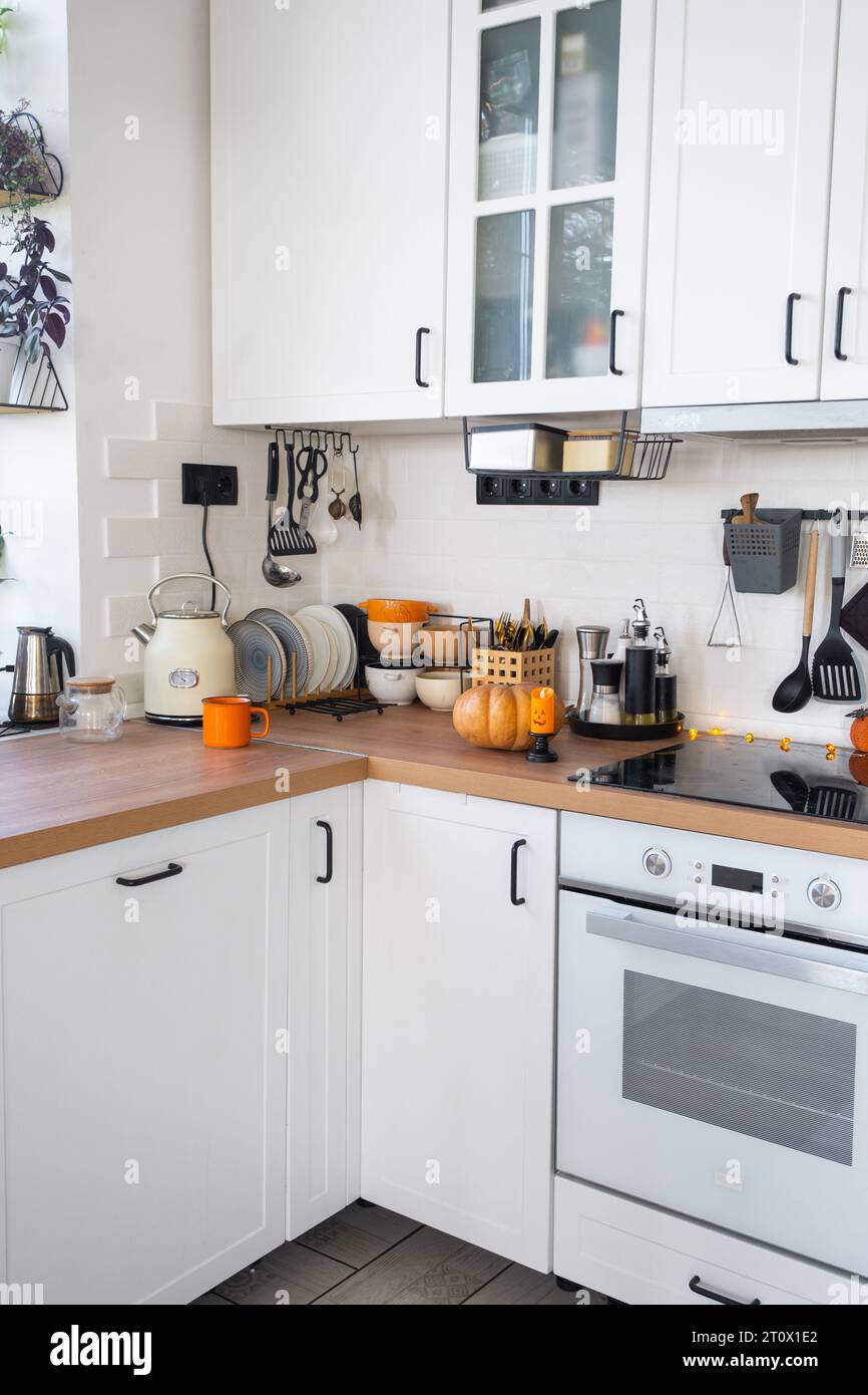 Dekor der weißen klassischen Küche mit Kürbissen für Halloween und Ernte. Herbststimmung im Innenraum, moderner Loft-Stil. Stockfoto