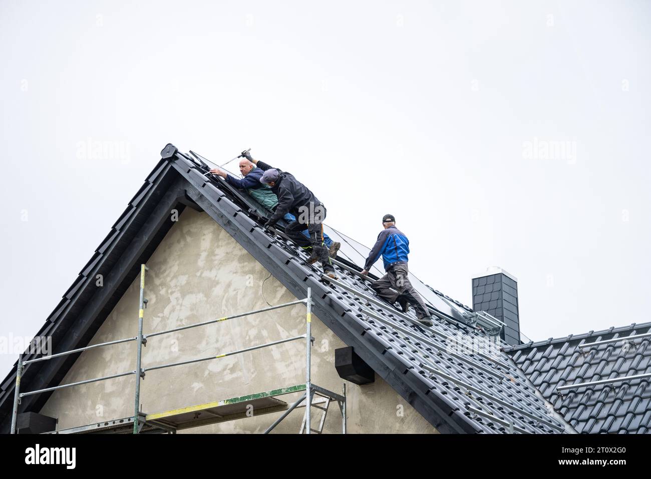 Techniker, die Solarpaneele auf dem Dach eines Einfamilienhauses installieren Stockfoto