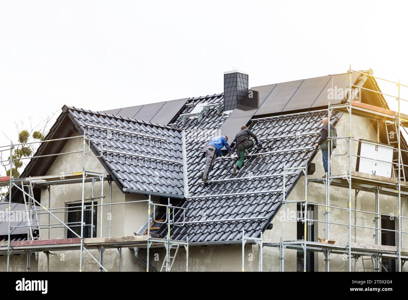Arbeiter, die Solarpaneele auf dem Dach eines Einfamilienhauses installieren Stockfoto