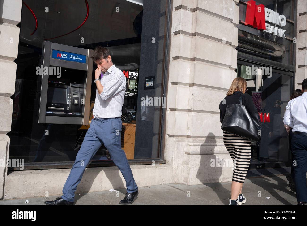 Am 9. Oktober 2023 in London, England, gehen die Mitglieder der Öffentlichkeit am Geldautomaten vor der Metro Bank-Filiale auf der Piccadilly vorbei. Die Metro Bank startet eine neue Kostensenkungsaktion, nachdem der Kreditgeber am Wochenende ein Rettungspaket in Höhe von 925 Millionen Pfund von Investoren gesichert hat. Metro war der erste neue Kreditgeber in Großbritannien seit 150 Jahren, als es 2010 eröffnet wurde. Es hat über Nacht bestätigt, dass Kunden in den letzten Tagen begonnen hatten, ihr Geld aus der Sorge um seine finanzielle Gesundheit. Stockfoto