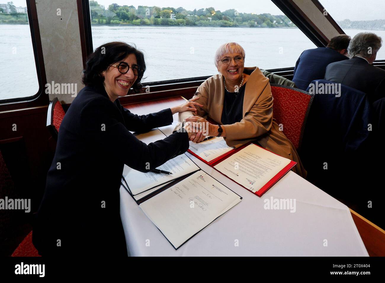Hamburg, Deutschland. Oktober 2023. Claudia Roth (Bündnis 90/die Grünen, r), Staatsministerin für Kultur und Medien, und Rima Abdul Malak, französische Kulturministerin, unterzeichnen Dokumente während einer Hafenfahrt durch den Hamburger Hafen. Das deutsche und das französische Kabinett treffen sich in der Hansestadt zu einem zweitägigen Rückzug. Quelle: Wolfgang Rattay/Reuters/Pool/dpa/Alamy Live News Stockfoto