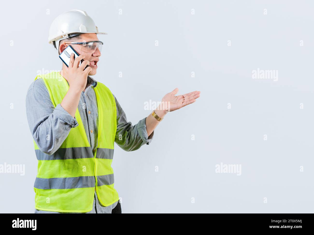 Junger Ingenieur, der auf dem Handy telefoniert. Bauingenieur spricht am Telefon isoliert auf weißem Hintergrund Stockfoto