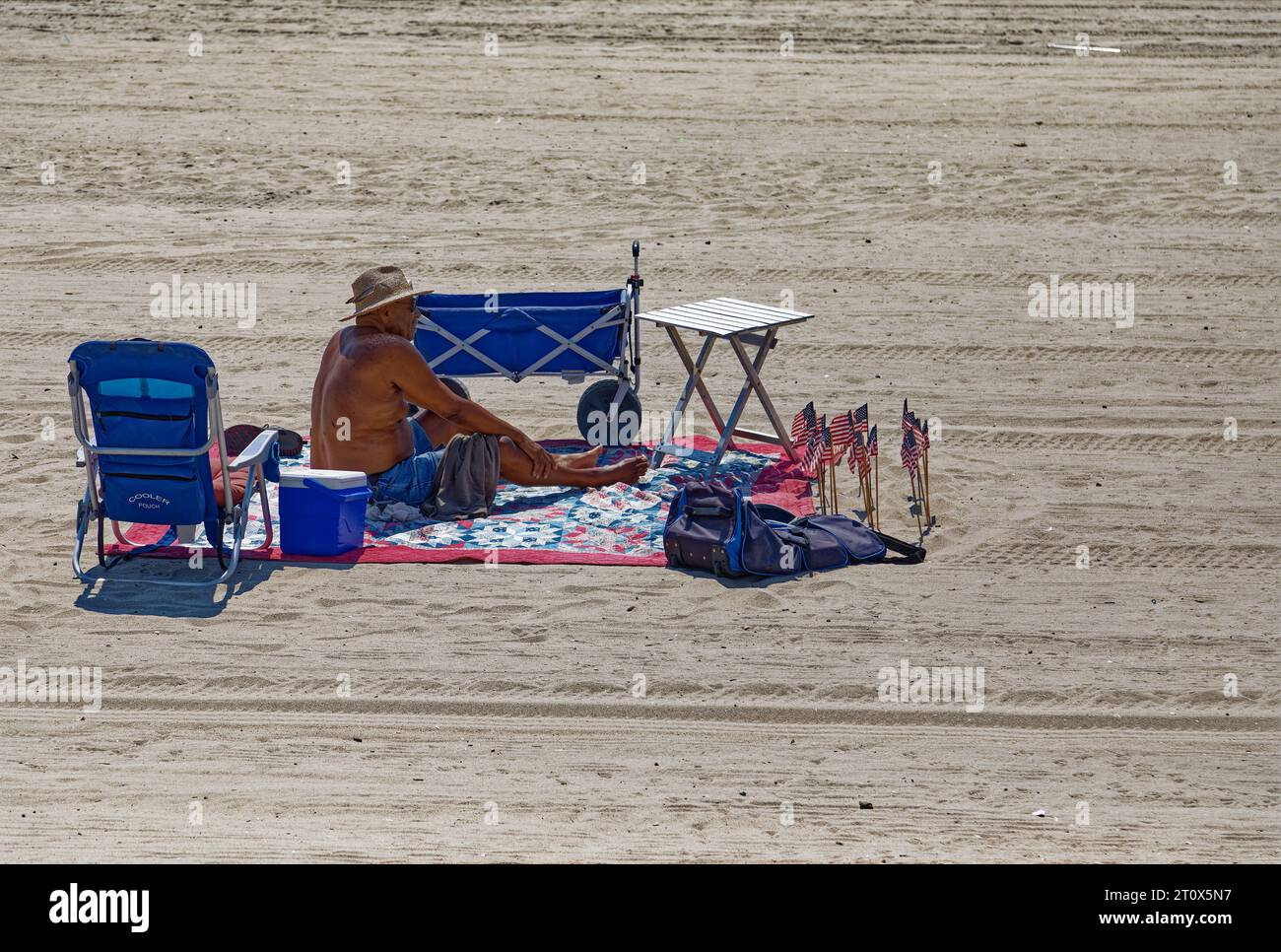 Ein einsamer Strandgänger scheint bereit zu sein, eine Weile am Atlantischen Strand des Riis Parks zu bleiben. Stockfoto