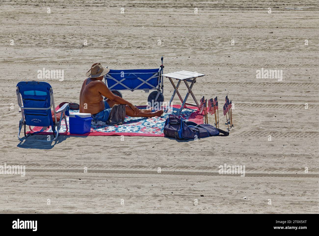 Ein einsamer Strandgänger scheint bereit zu sein, eine Weile am Atlantischen Strand des Riis Parks zu bleiben. Stockfoto