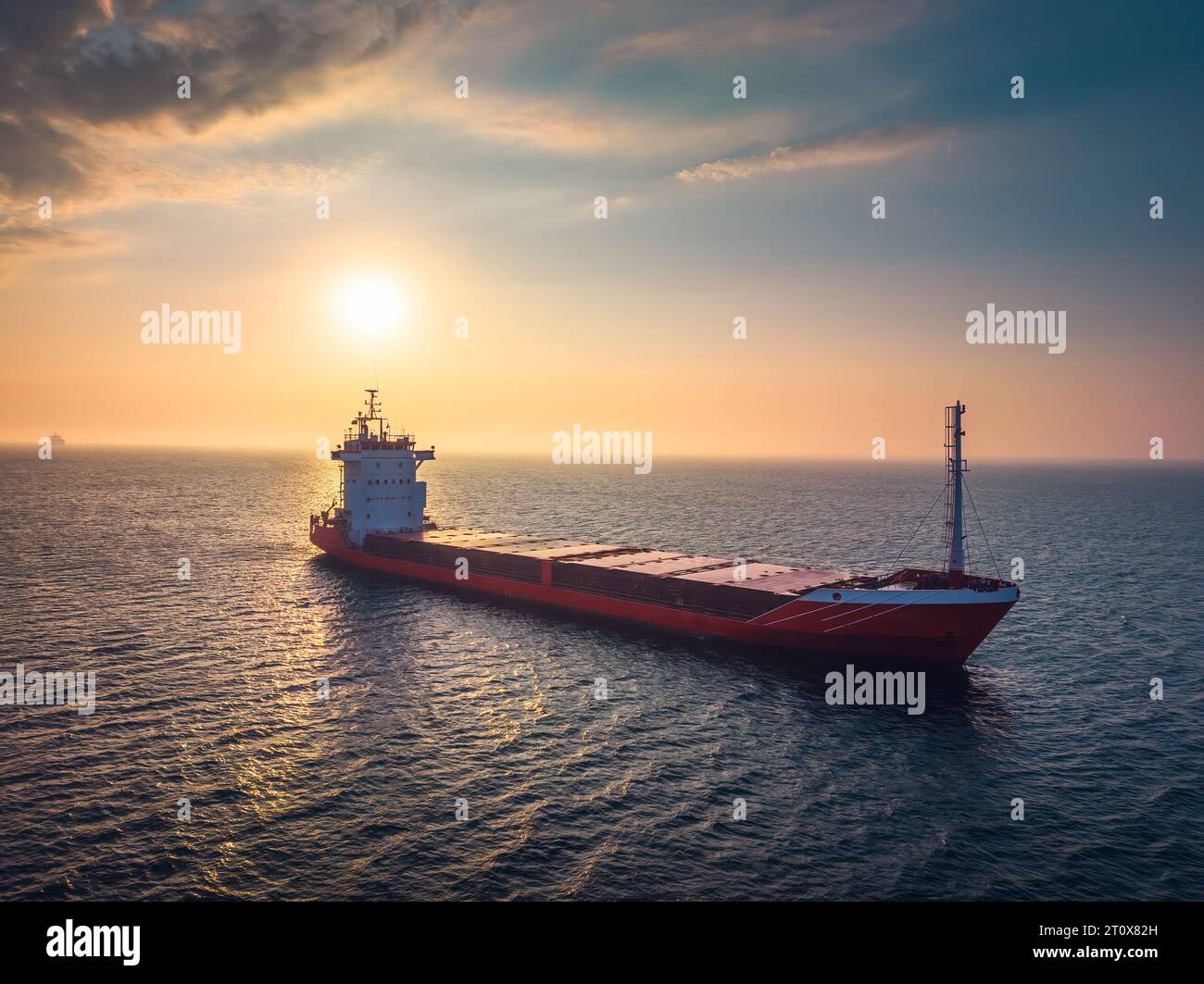 Sonnenaufgang über dem Meereshorizont und Segeln von Industriegutschiffen in tiefblauem, offenem Wasser, aus der Luft Stockfoto