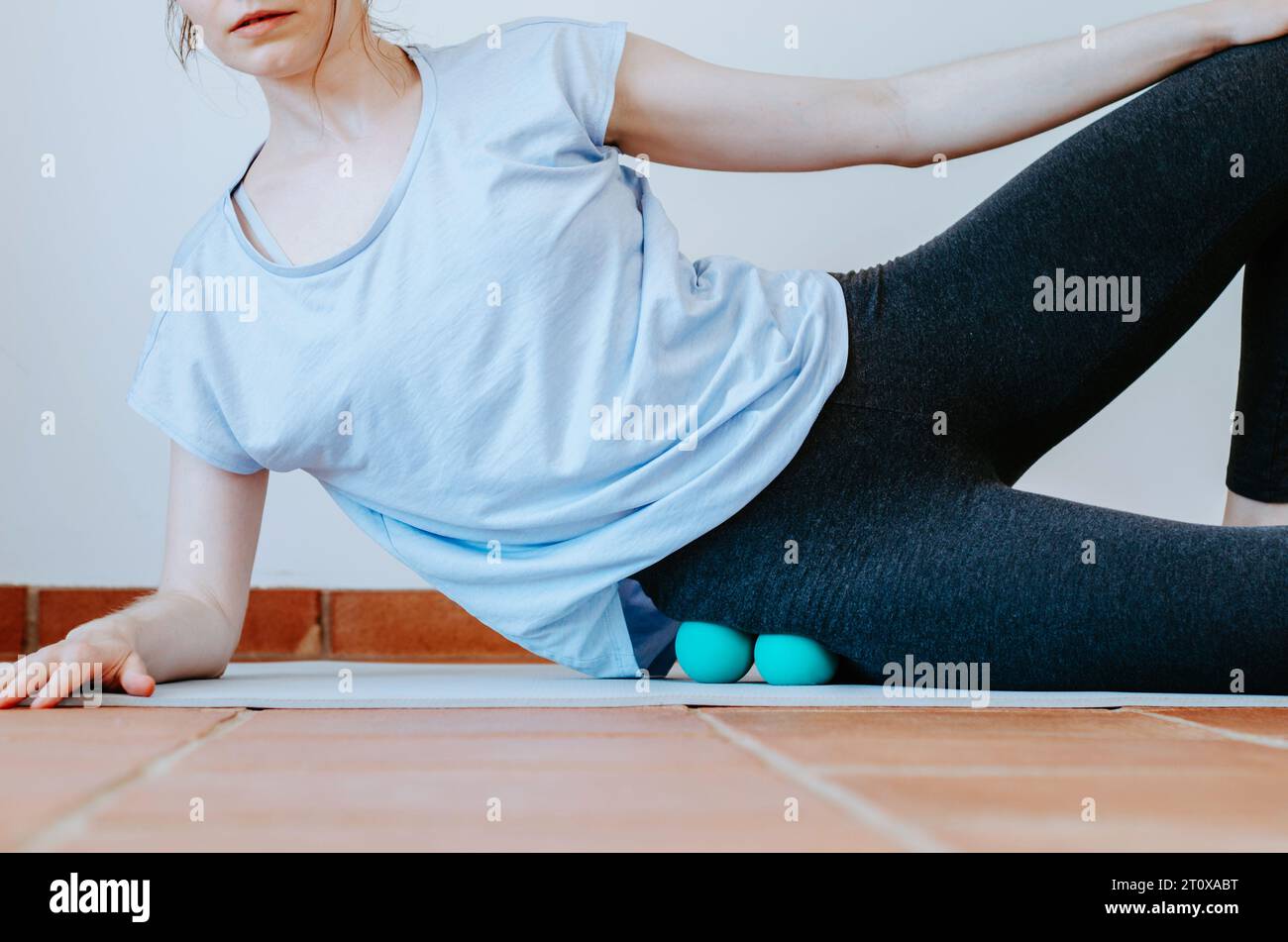 Frau, die Gluteus-Selbstmassage mit Therapiebällen macht Stockfoto