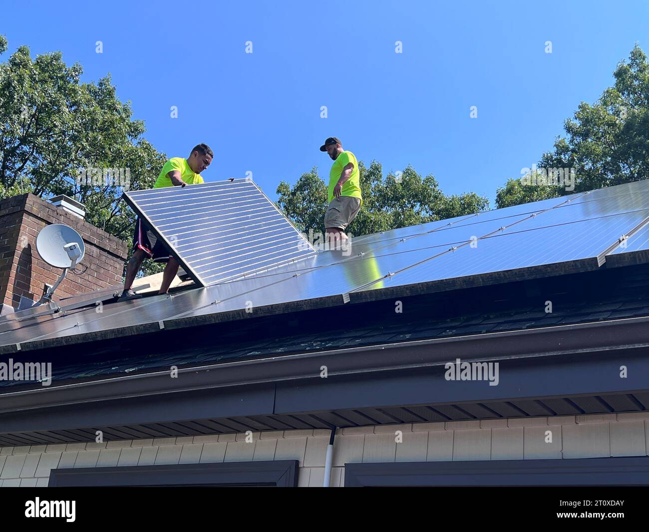 Arbeiter, die Solarpaneele auf einem Wohndach installieren Stockfoto
