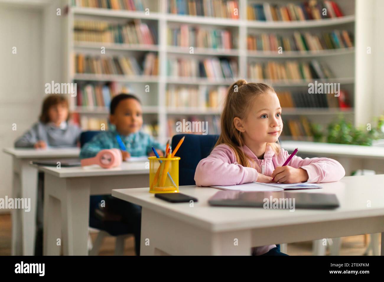 Achtsame Schulkinder, die Lehrer im Unterricht hören Stockfoto