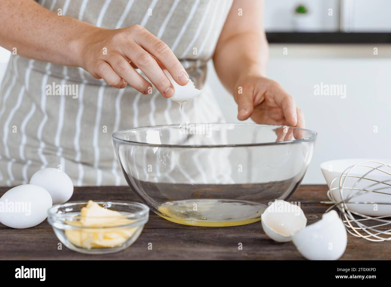 Ein Bäcker oder Koch zerteilt ein rohes Ei in eine Schüssel. Teig zum Backen oder Brot kochen, Frühstück mit Eiern machen, Morgenroutine. Hausgemachte oder handgemachte Bak Stockfoto