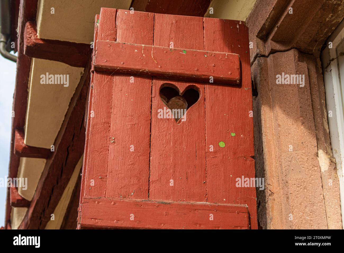 Detail eines alten roten Holzladens mit Loch in Herzform auf Fachwerkhaus in süddeutscher Kleinstadt Stockfoto