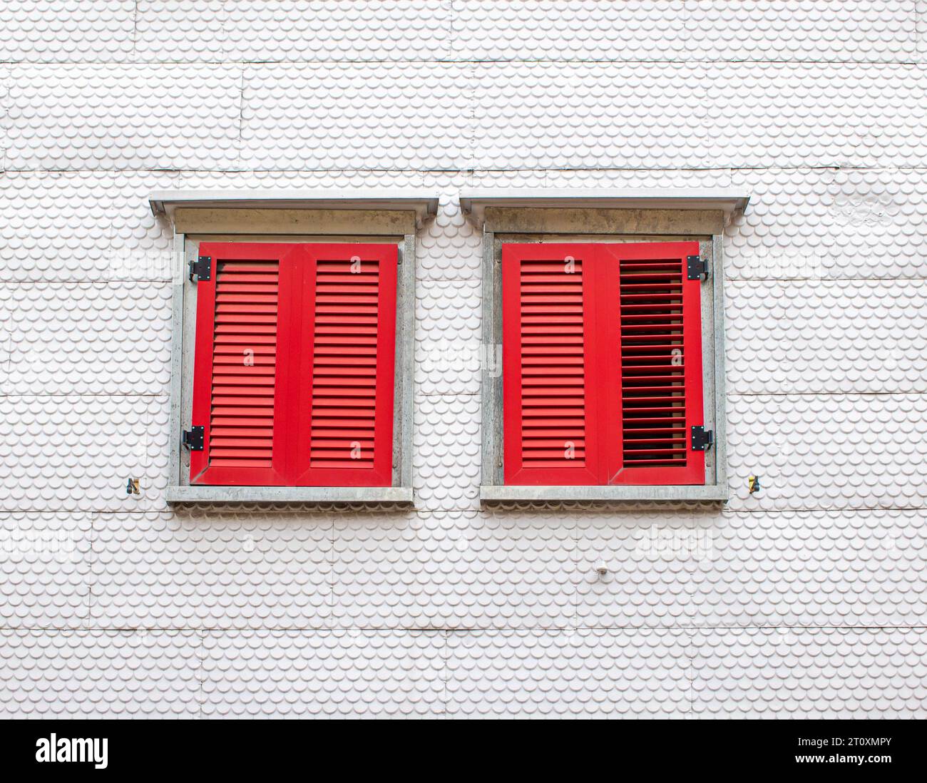 Zwei rote Holzläden an einer weißen Fassade im Stil von Holzschindelverkleidungen Stockfoto