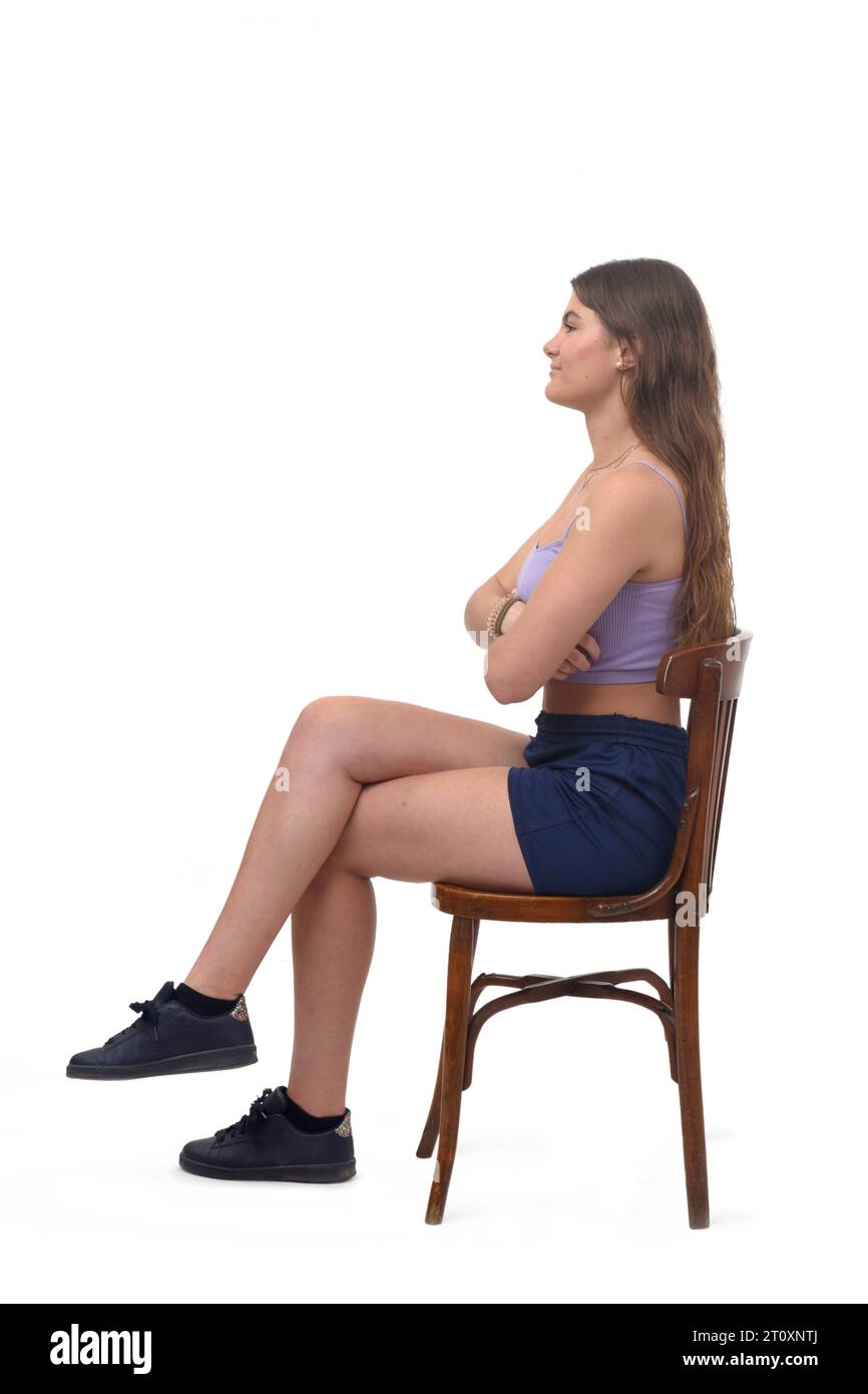 Seitenansicht eines jungen Mädchens, das auf Stuhlarmen und Beinen sitzt, die auf weißem Hintergrund überkreuzt sind Stockfoto