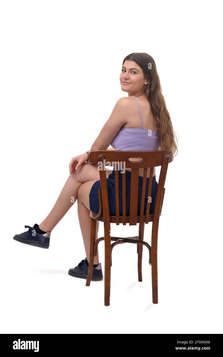 Ein junges Mädchen, das auf einem Stuhl sitzt und auf weißem Hintergrund in die Kamera blickt Stockfoto