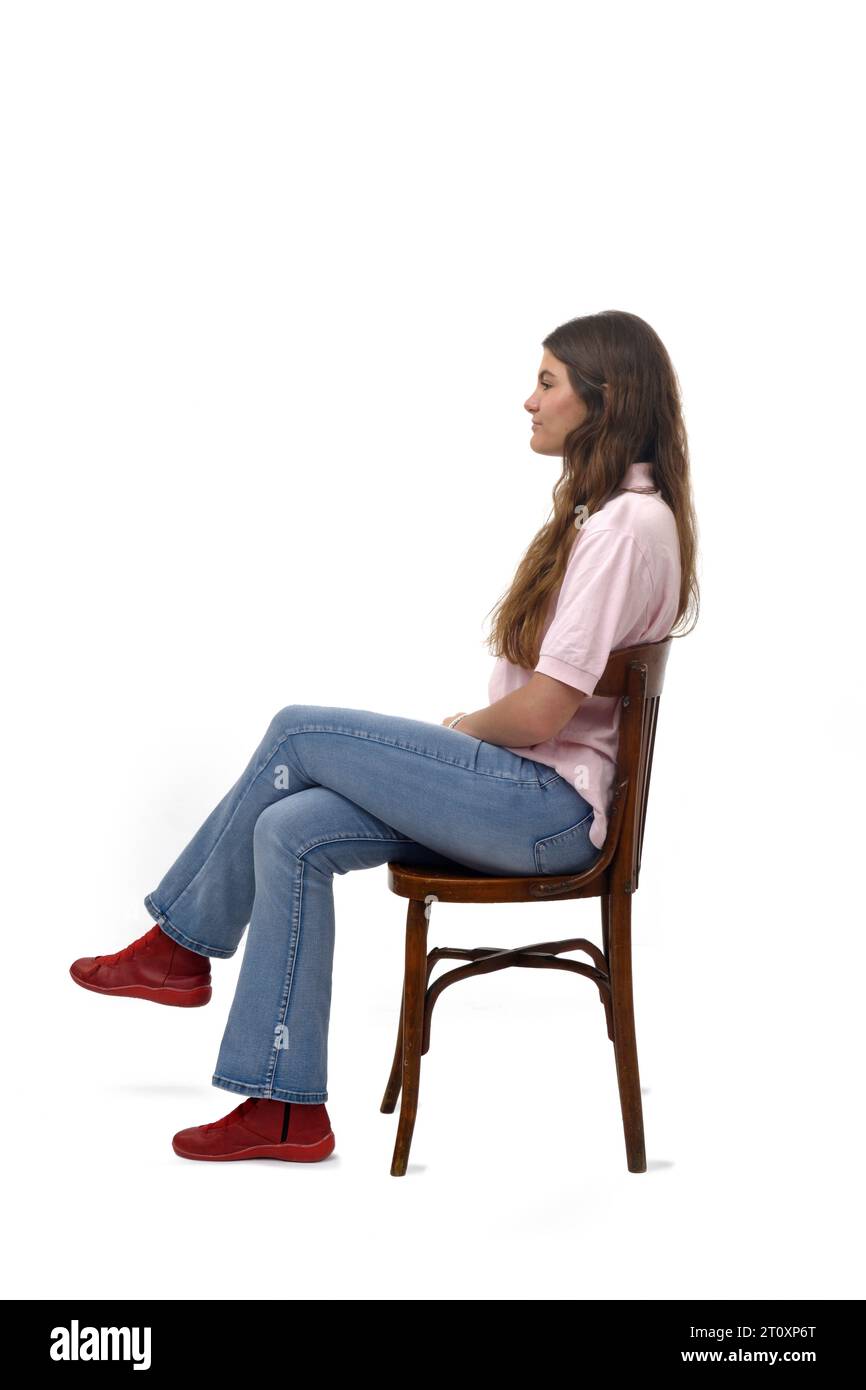 Seitenansicht eines jungen Mädchens, das auf einem Stuhl sitzt, mit einem Kreuz auf weißem Hintergrund Stockfoto