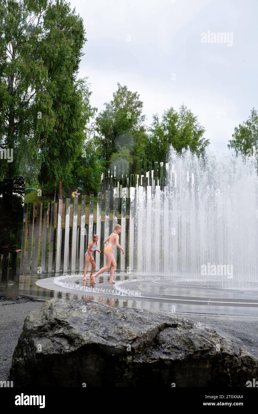 Zwei Mädchen spielen in einem Brunnen. Blick auf Kunstwerke im Kistefos Museum, einem Skulpturengarten im Freien in der Nähe von Jevnaker, Viken, Norwegen. Stockfoto