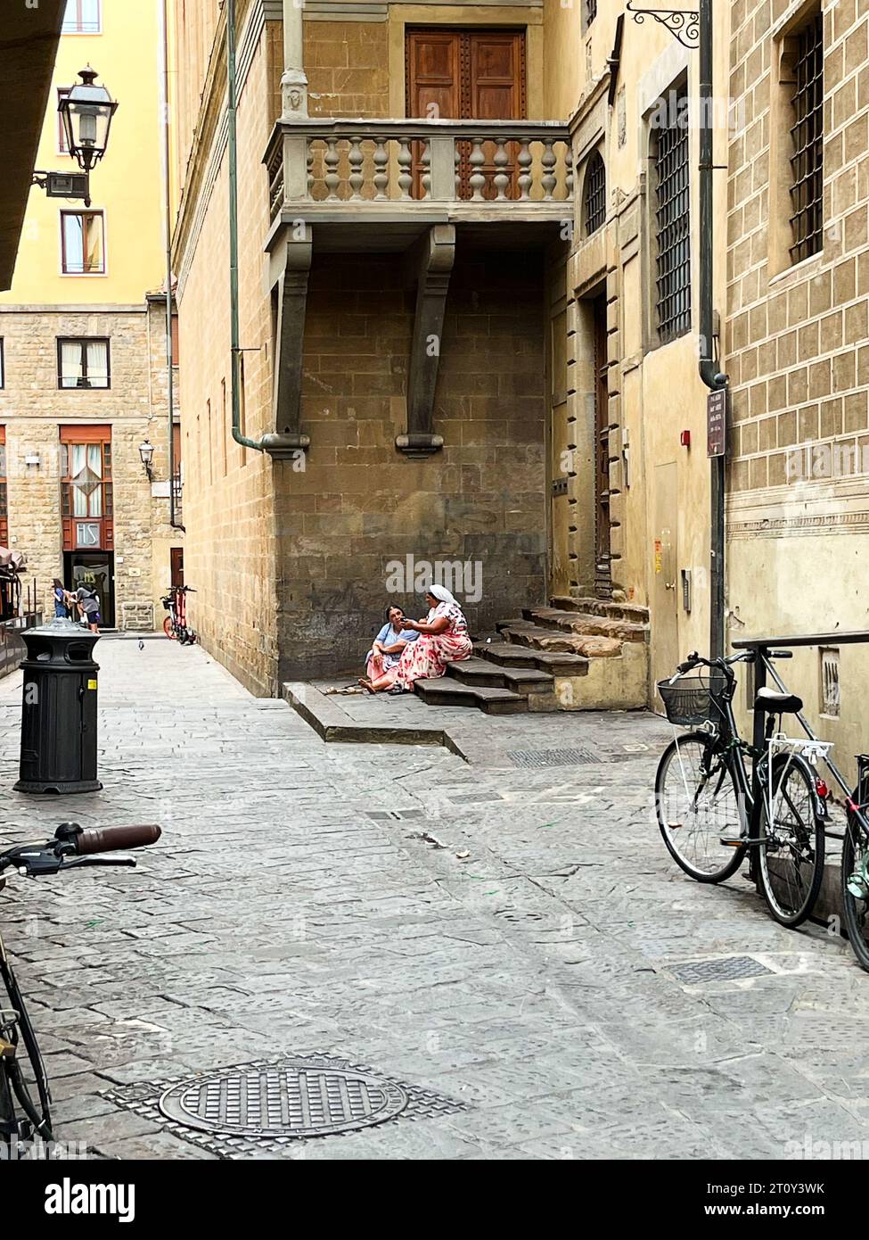 Florenz, Utaly. September 2023. Zwei Frauen betteln und sitzen auf einer kleinen Treppe in Florenz. Hochwertige Fotos Stockfoto