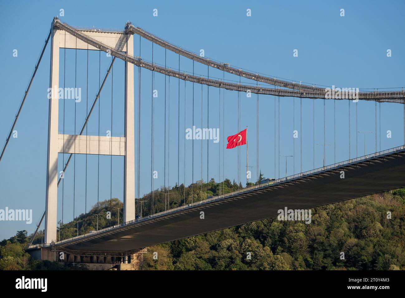 Bosporus-Brückenfotografie aus dem unteren Winkel mit blauem Himmel, Wald und türkischer Flagge in İstanbul. Stockfoto