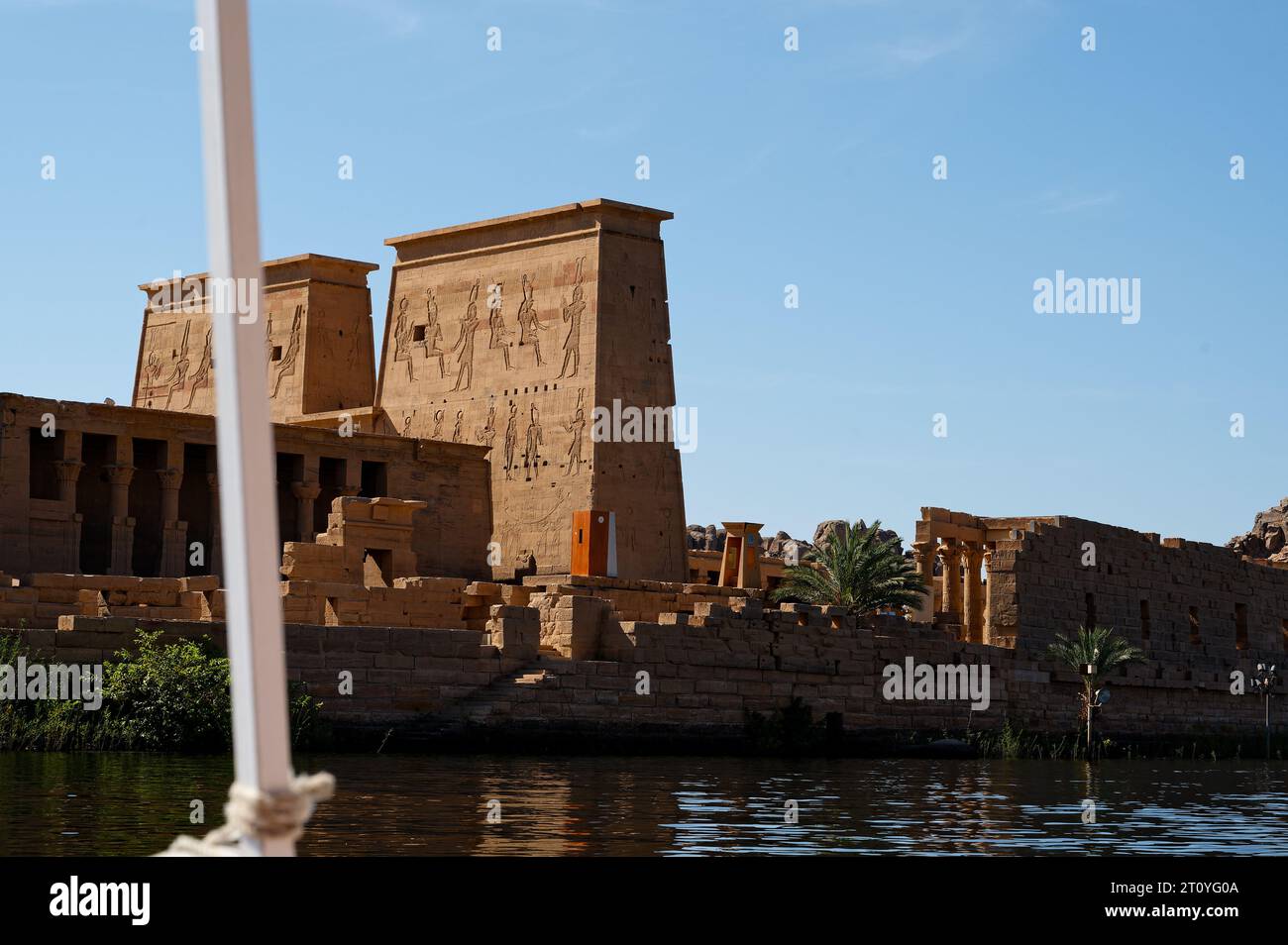 Foto von einer kleinen Fähre, während es sich anmutig dem berühmten philae-Tempel nähert, eingebettet in das ruhige Wasser des nasser-Sees. Stockfoto