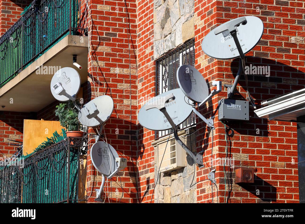 Mehrere Satellitenfernsehschüsseln auf der Seite eines Wohnhauses in NYC. Dish Network, DirecTV Digital Satellite Broadcast Antennen. Stockfoto