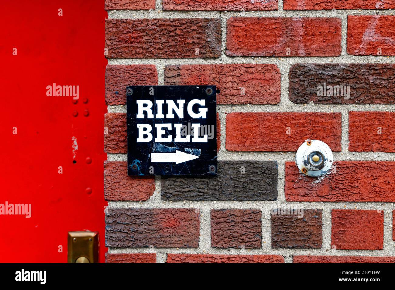 Ein Ring Bell Schild neben einer runden Türglocke an einer roten Ziegelwand Stockfoto