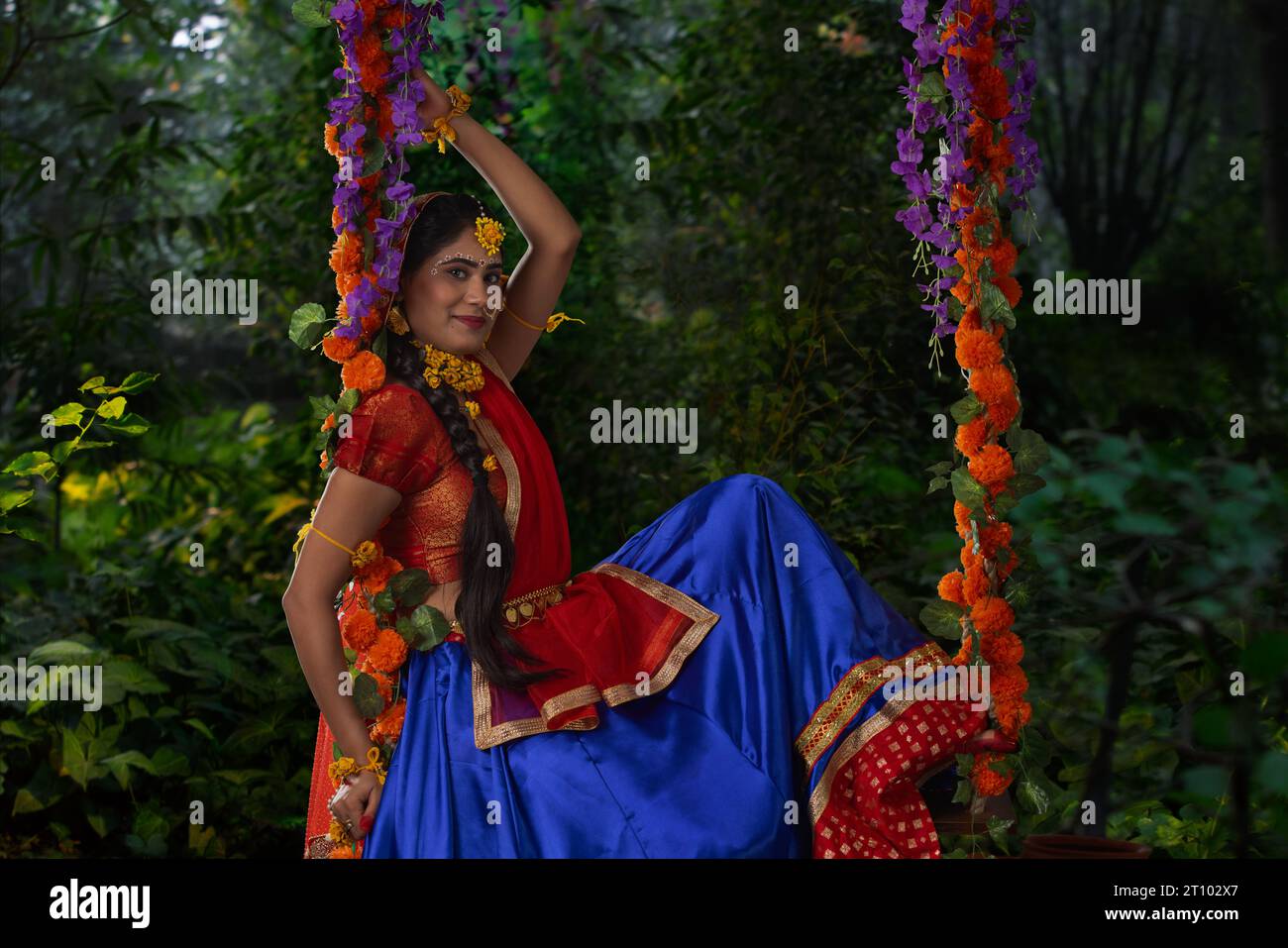 Eine junge Frau, verkleidet als Radha und sitzend auf einer Schaukel anlässlich von Janmashtami Stockfoto