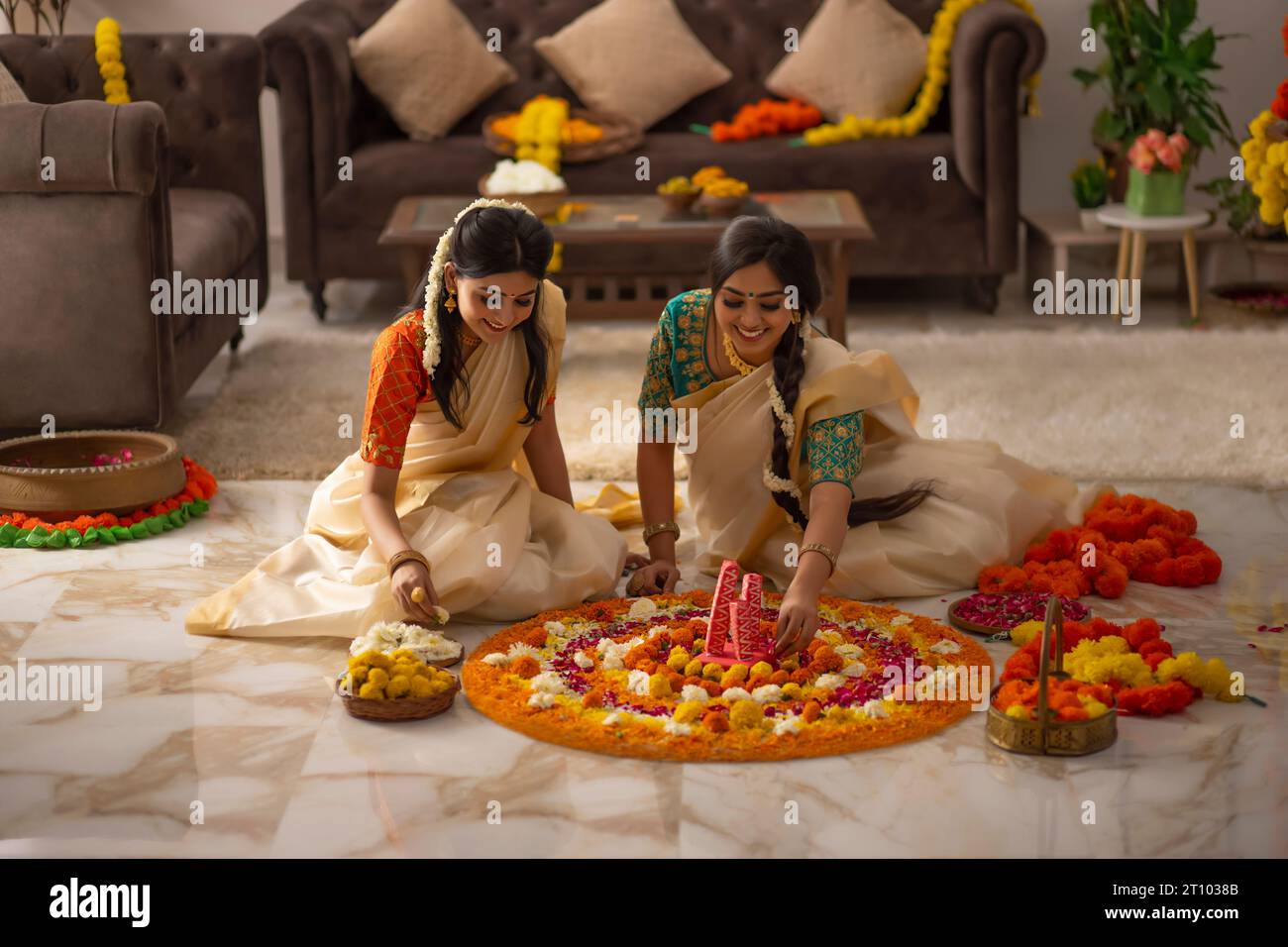 Südindische Frauen in weißem Saree dekorieren den Boden mit Blumen, um Onam zu feiern Stockfoto