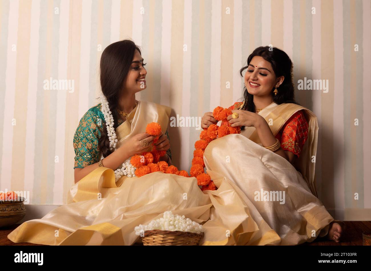 Frauen in weißen Saree-Girlanden Blumen, um Onam zu feiern Stockfoto