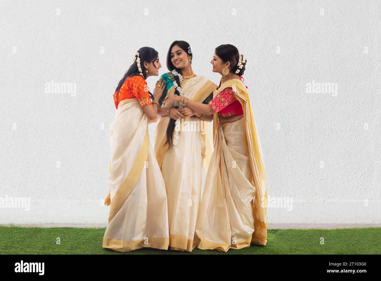 Südindische Frauen in weißem Saree stehen zusammen und reden über Onam Stockfoto