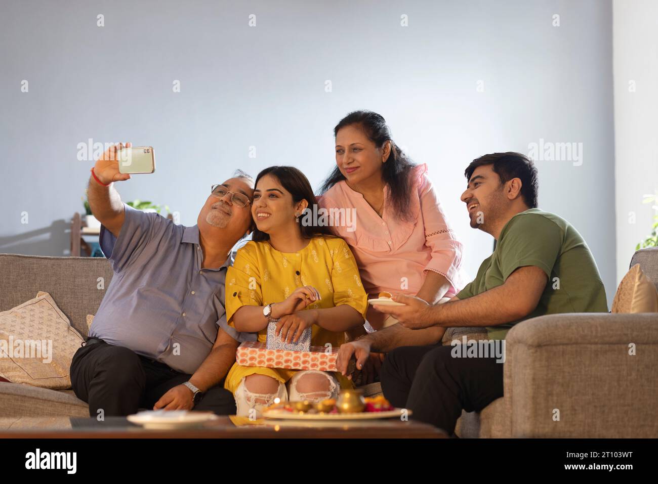 Ein Senior-Mann, der Selfie seiner Familie macht, während er zu Hause auf Raksha Bandhan sitzt Stockfoto