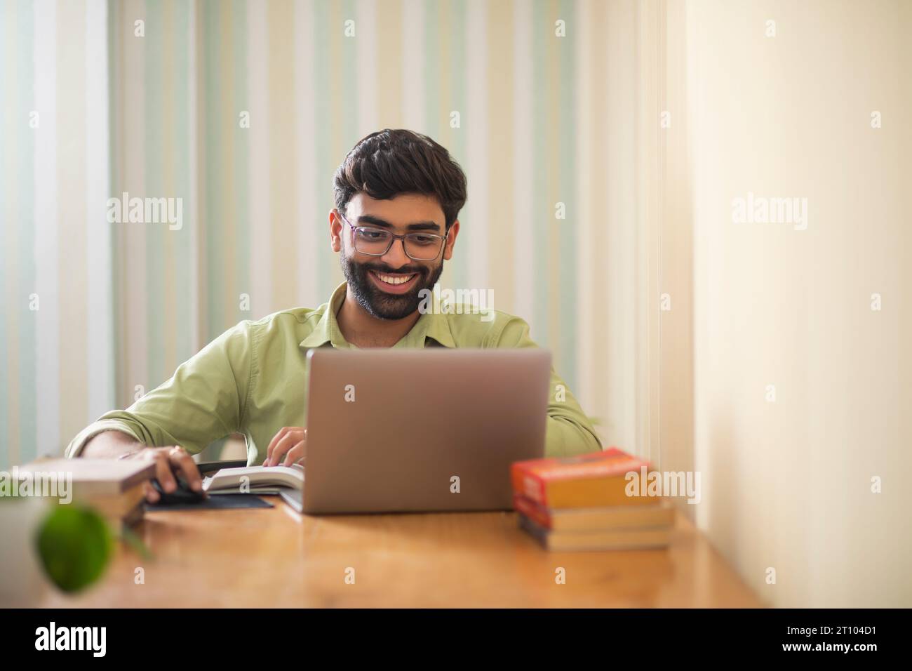 Junger Mann, der mit Laptop in seinem Heimbüro arbeitet Stockfoto