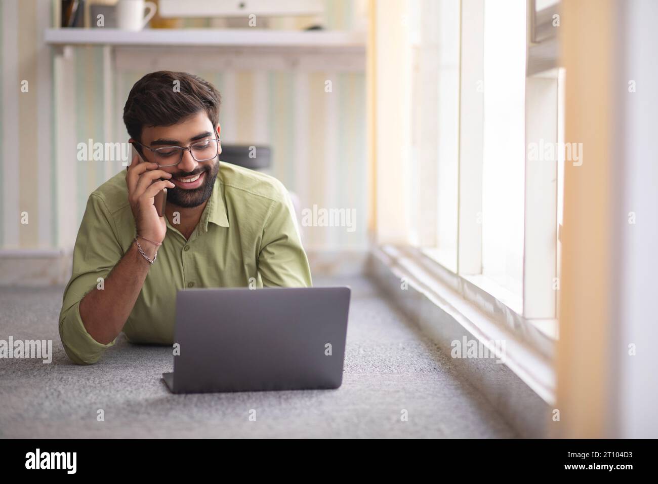 Junger Mann Gespräch am Handy mit Laptop Stockfoto