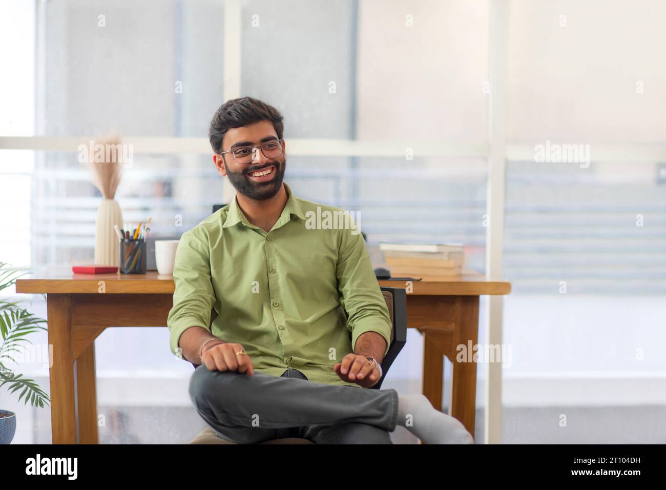 Porträt eines selbstbewussten jungen Mannes, der in seinem Heimbüro am Schreibtisch sitzt Stockfoto