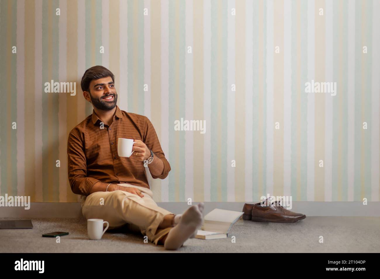 Junger Mann, der in seinem Heimbüro eine Kaffeepause macht Stockfoto